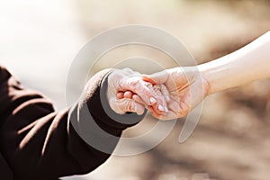 Senior woman holding hands with young caretaker photo