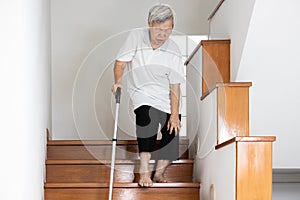 Senior woman holding her pain knee with hand while walking down the stairs,elderly suffering from Osteoarthritis of the knee,