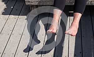 Senior woman is holding her wet feet up in sun to dry off, evaporate water