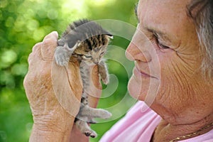 Senior woman holding little kitten