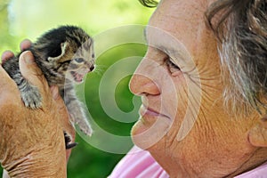 Senior woman holding little kitten