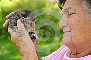 Senior woman holding little kitten