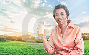 Senior woman is holding milk for calcium food and healthy lifestyle concept with nature background