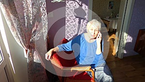 Senior woman holding mobile phone at home.