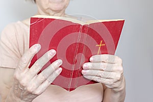 Senior woman holding an old holy bible in hands, Elder woman holding New Testament and praying