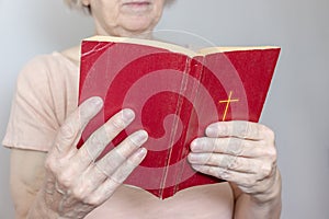 Senior woman holding an old holy bible in hands, Elder woman holding New Testament and praying