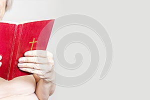 Senior woman holding an old holy bible in hands, Elder woman holding New Testament and praying, copy space