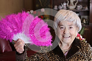 Senior woman holding plumy pink feather hand fan