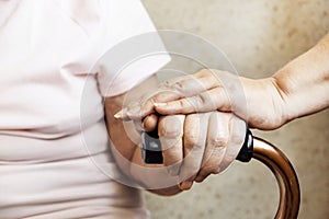 Senior woman holding quad cane handle in elderly care fecility.