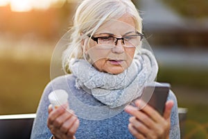 Woman holding smartphone and pill bottle