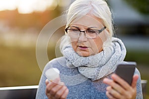 Woman holding smartphone and pill bottle