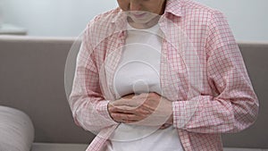 Senior woman holding stomach, suffering from gastritis problems, health care