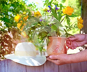 Senior woman holding summer bouquet in clay jug, summer day