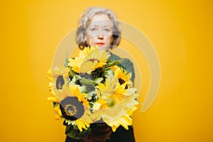 Senior woman holding a sunflower bouquet