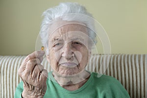 A senior woman holding a vitamin capsule