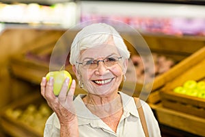 Senior woman holding and watching a green apple