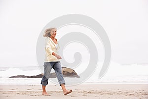 Senior Woman On Holiday Running Along Beach