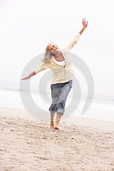 Senior Woman On Holiday Running Along Winter Beach