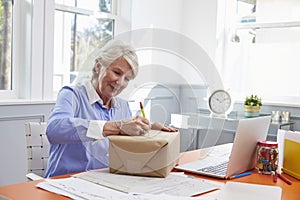 Senior Woman At Home Addressing Package For Mailing