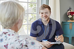 Senior woman at home with male care worker making notes
