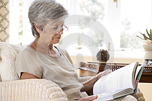 Senior woman at home reading book photo