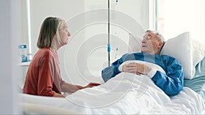 Senior woman, hospital and husband in bed with cancer, illness or sick in conversation for support. Elderly patient, man