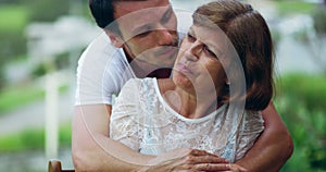 Senior woman, hugging and adult child kissing his mother on the cheek with love, care and happiness in a park. Happy