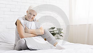 Senior woman hugging white pillow at home