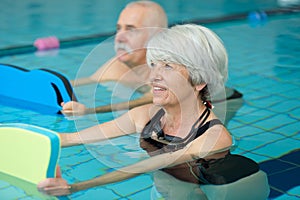 senior woman and husband exercising in swimming pool