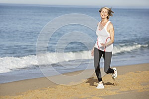 Senior Woman Jogging Along Beach