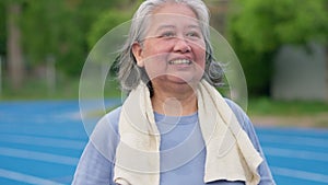 Senior woman jogging in outdoor stadium. Elderly female person is happy about cardio for health and wellness while walking or