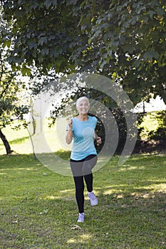 Senior woman jogging through park