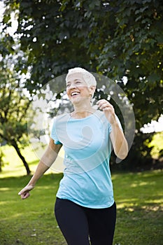 Senior woman jogging through park