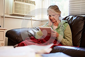 Senior Woman Keeping Warm Under Blanket With Photograph