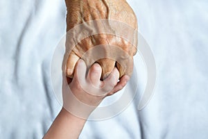 Senior woman and a kid hands joined together. Grandparent ant grand child. Concept of family and change of generations