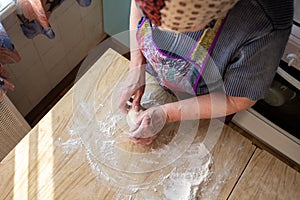 Senior woman kneading the dough in her home kitchen