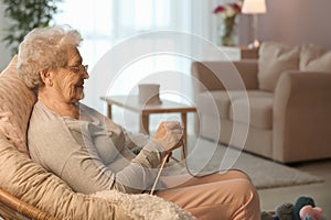 Senior woman knitting in lounge chair at home
