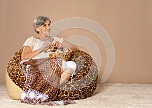 Senior woman knitting sitting in armchair