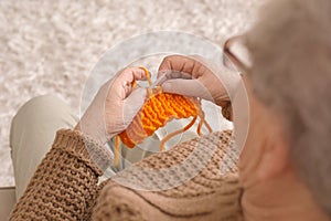 Senior woman knitting sweater at home, closeup
