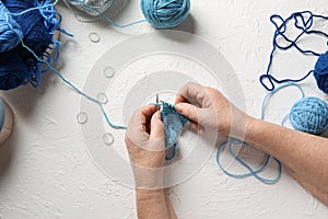 Senior woman knitting sweater on light background