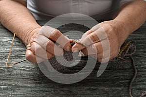 Senior woman knitting sweater at table, closeup