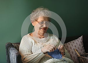 Senior woman knitting warm sock at home