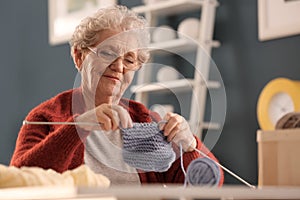 Senior woman knitting warm sock at home