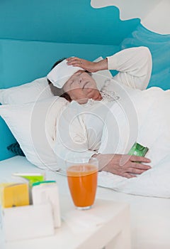 Senior woman laid ill in the bed with medicament and pillows, photo