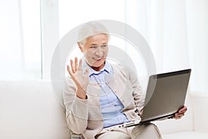 Senior woman with laptop having video chat at home