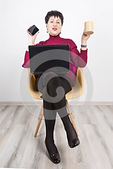 Senior woman with laptop and mobile phone isolated on grey studio background