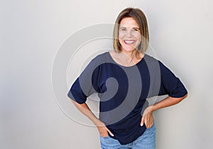 Senior woman laughing against gray wall