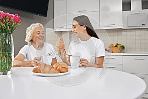 Senior woman laughing with granddaughter in kitchen.