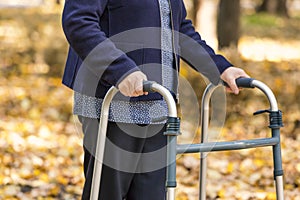 Senior woman legs walking with walker in autumn park