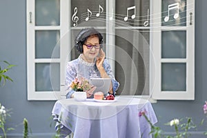 Senior woman is listen music and pose share good news at social media via computer tablet